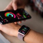 Person trägt Smart Watch und hält ein iPhone in der Hand