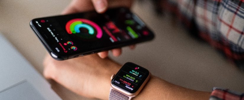 Person trägt Smart Watch und hält ein iPhone in der Hand